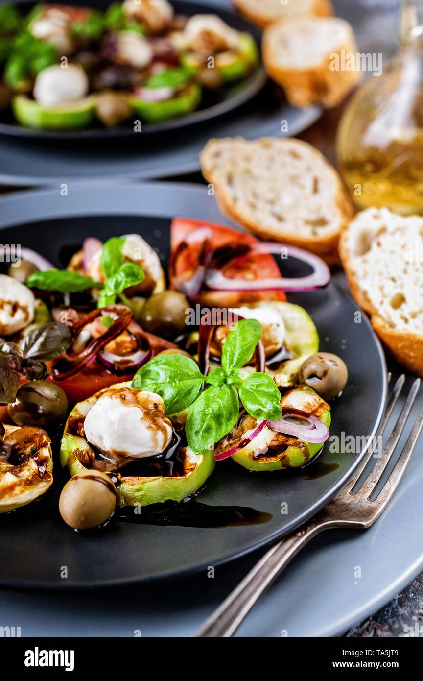 Close-up of ciabatta, Italian salad with grilled vegetables, basil and balsamic sauce on rust background. Mediterranean Kitchen. Close-up Stock Photo