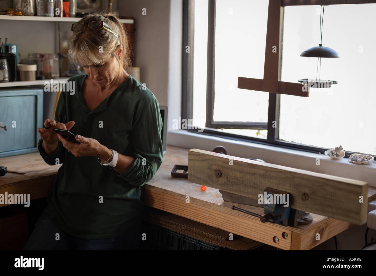 Female carpenter using mobile phone in workshop Stock Photo