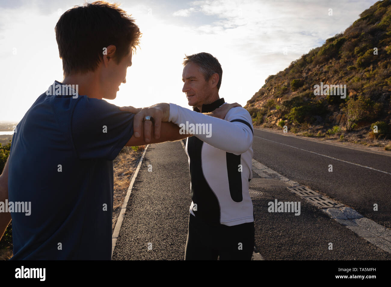 Father and son doing stretching exercise on road Stock Photo