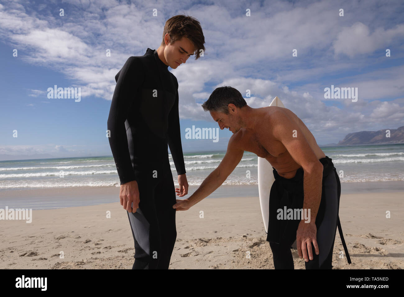 Father assist son to ride surfboard at beach Stock Photo