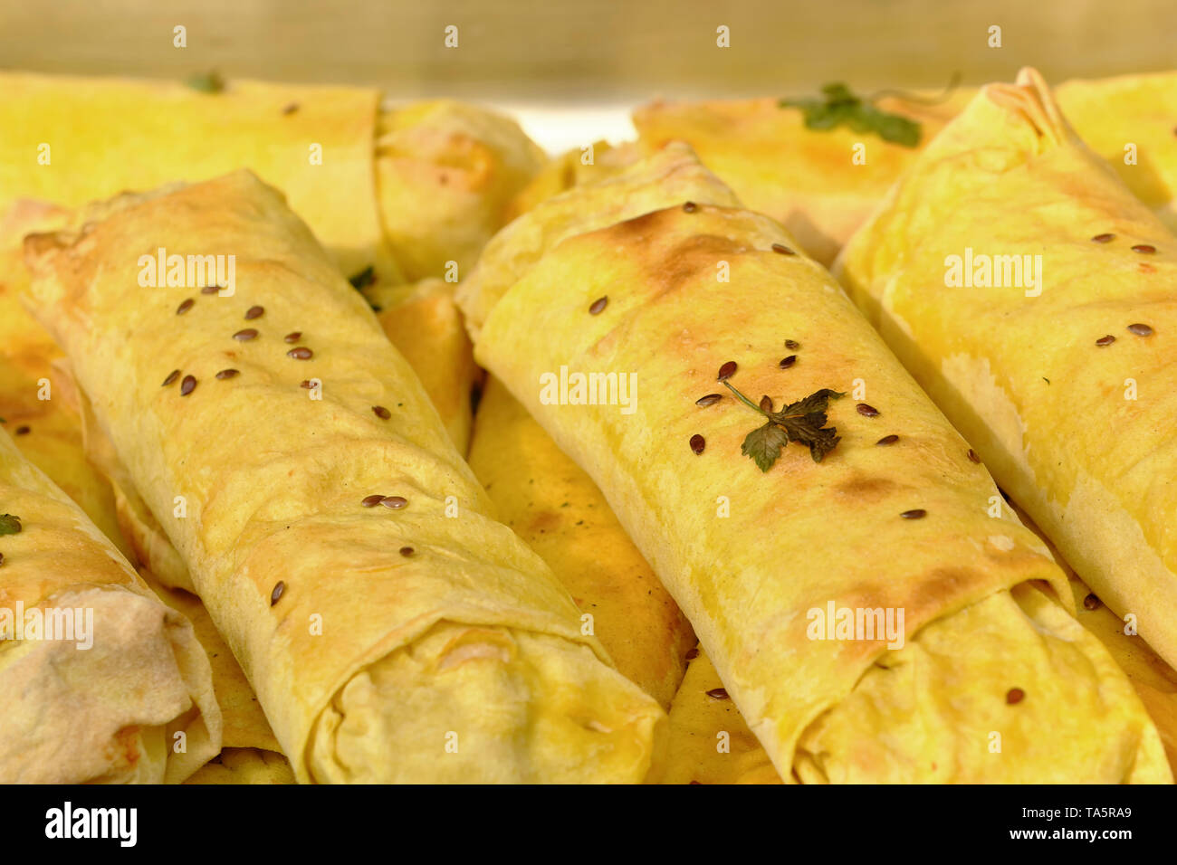 Baked pancakes with various meat, cheese and vegetable fillings cooked outdoors on a bright sunny spring day Stock Photo