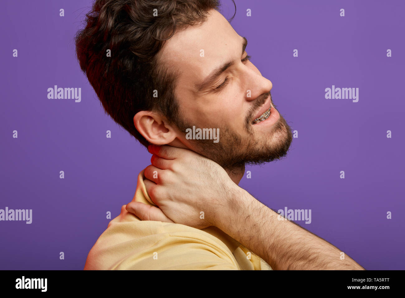 man has cervical rediculopathy. close up cropped photo.whisplash, sudden jolt to the neck . cancer concept. bearded pleasant man massaging his neck. Stock Photo