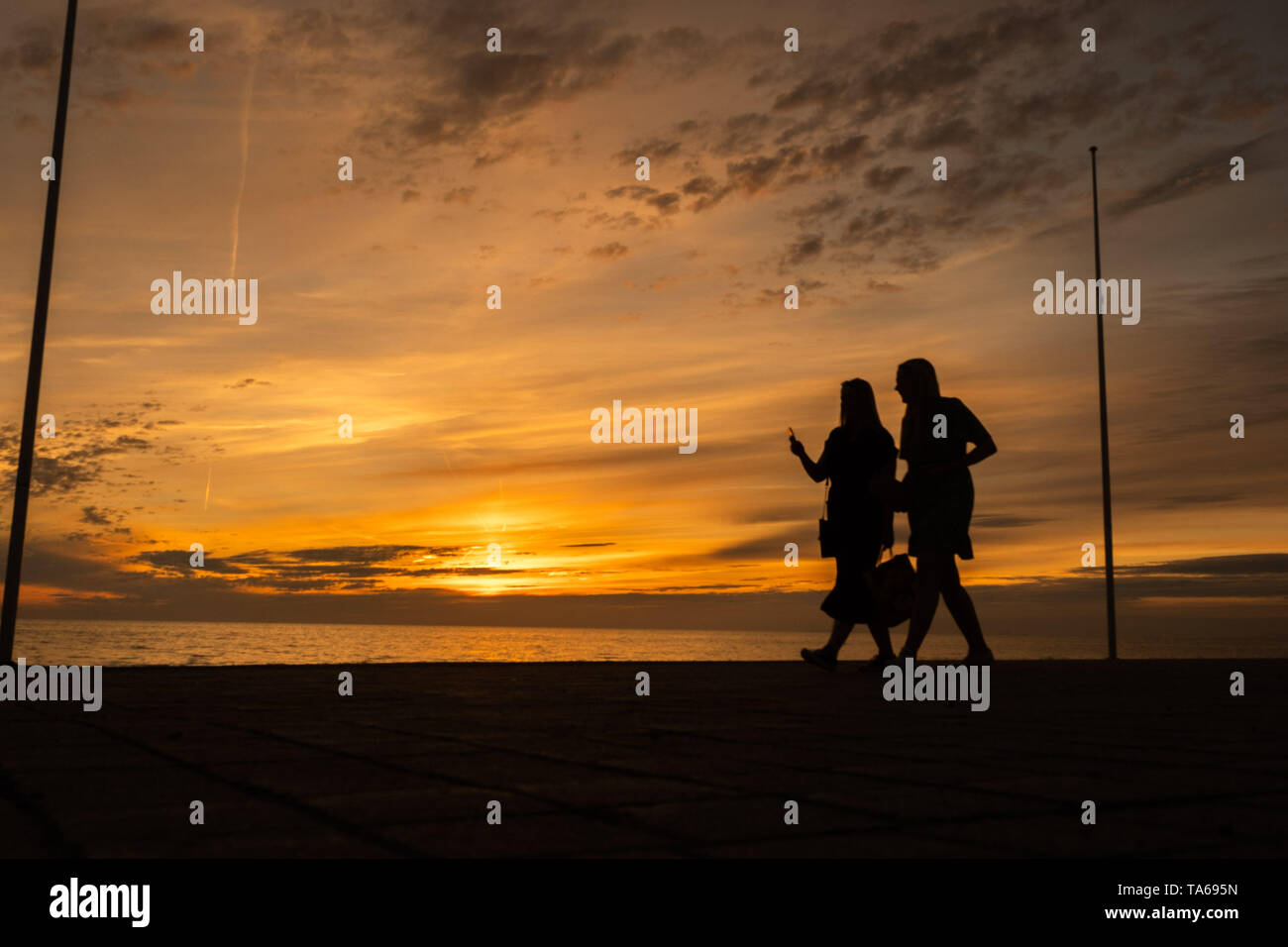 Aberystwyth Wales UK, Wednesday 22 May 2019  UK Weather: Two women  silhouetted  strolling along the seafront promenade at sunset in Aberystwyth on a mild May evening, at the end of a day of warm spring sunshine on the west coast of Wales. photo credit: Keith Morris / Alamy Live News Stock Photo
