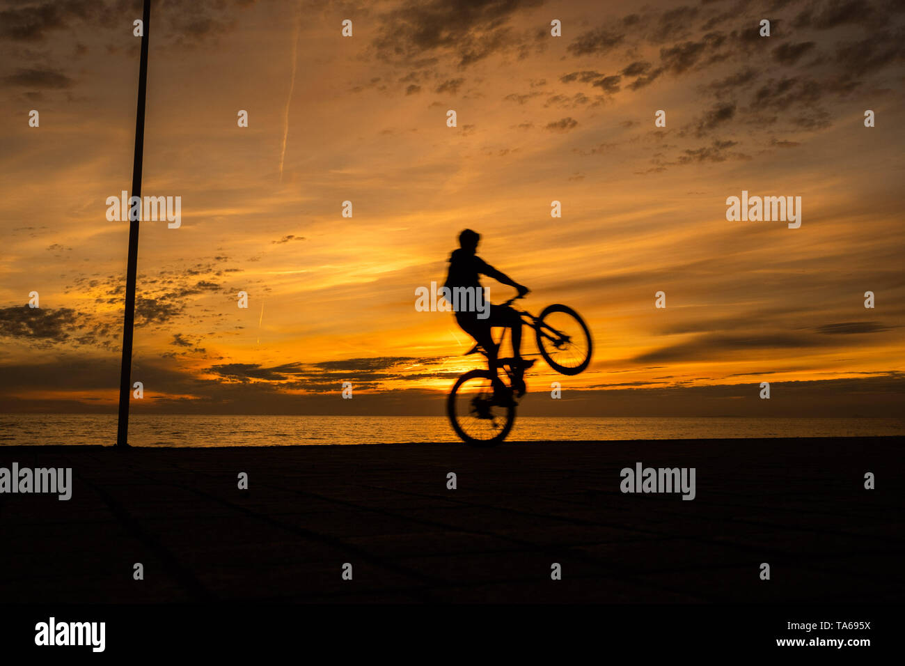 Aberystwyth Wales UK, Wednesday 22 May 2019  UK Weather: People silhouetted  cycling along the seafront promenade at sunset in Aberystwyth on a mild May evening, at the end of a day of warm spring sunshine on the west coast of Wales. photo credit: Keith Morris / Alamy Live News Stock Photo