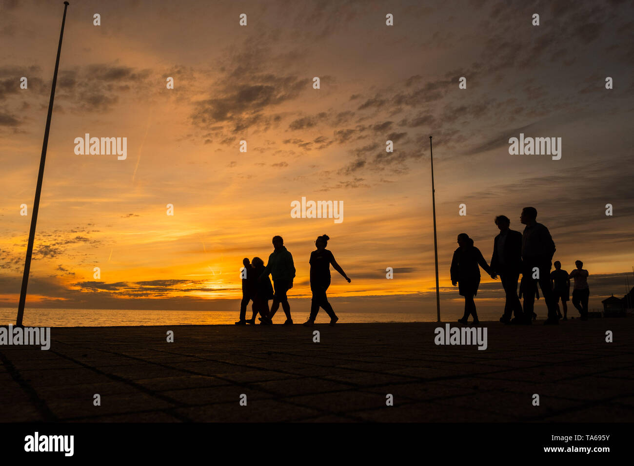Aberystwyth Wales UK, Wednesday 22 May 2019  UK Weather: People silhouetted  strolling along the seafront promenade at sunset in Aberystwyth on a mild May evening, at the end of a day of warm spring sunshine on the west coast of Wales. photo credit: Keith Morris / Alamy Live News Stock Photo