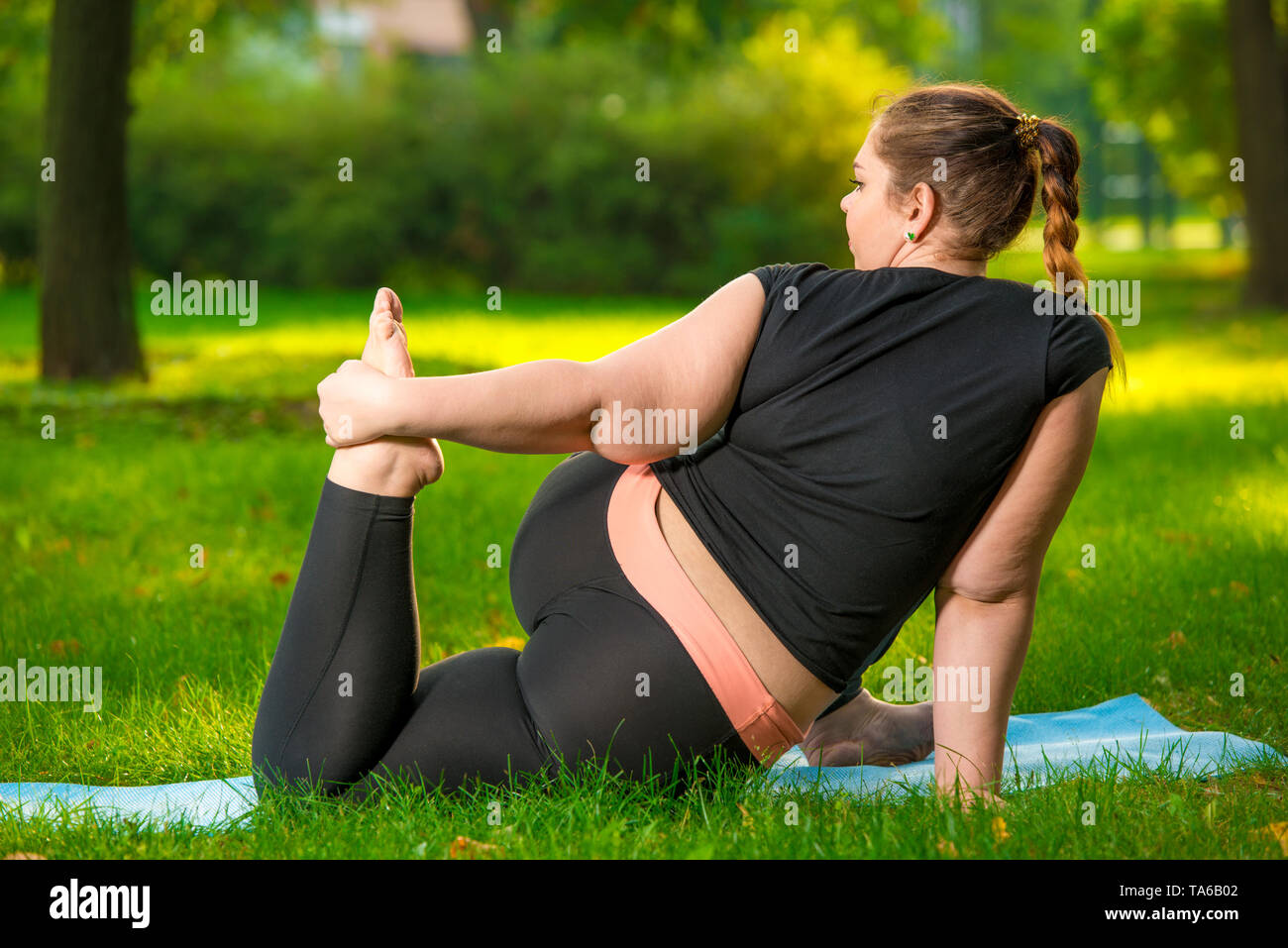 Asian Fat Woman Doing Exercise And Stretching By Yoga On The Grass
