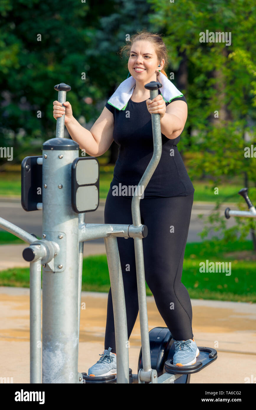 portrait of an active fat woman without complexes is engaged on a stepper simulator in the park Stock Photo