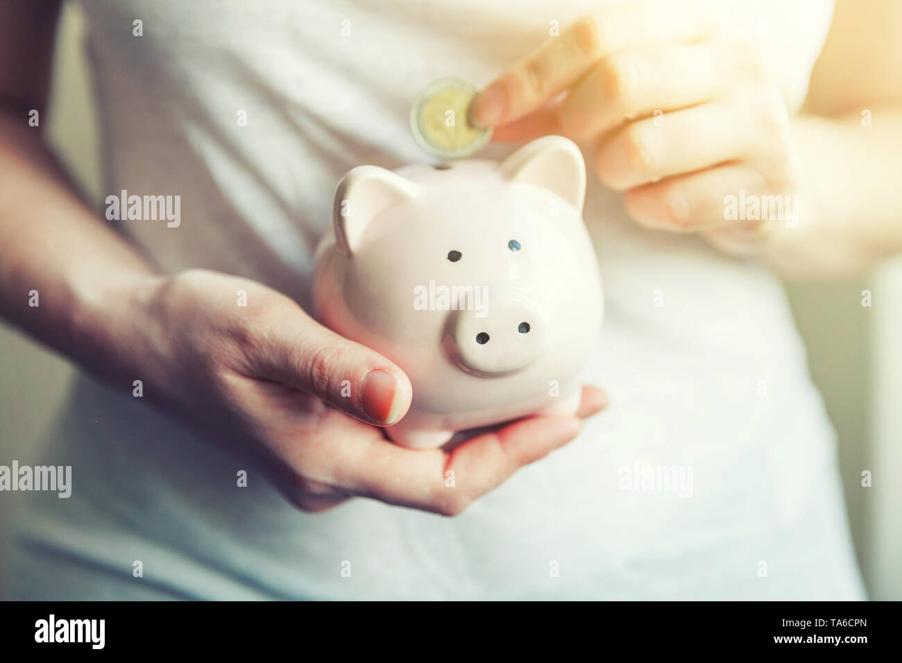 Female woman hands holding pink piggy bank and putting money Euro coin ...