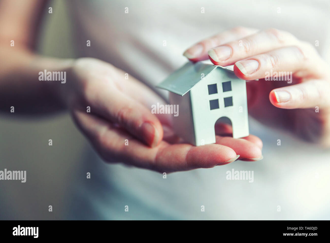 Female woman hands holding small miniature white toy house. Mortgage property insurance dream moving home and real estate concept Stock Photo