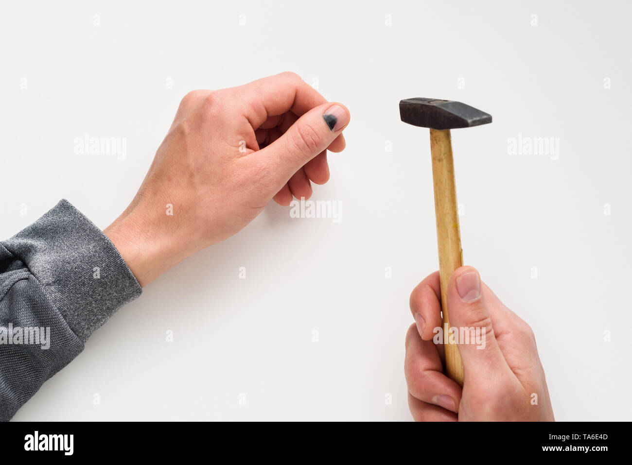 Hammer on the finger. Black thumbnail. Injury in violation of occupational safety. Men hands on white background Stock Photo