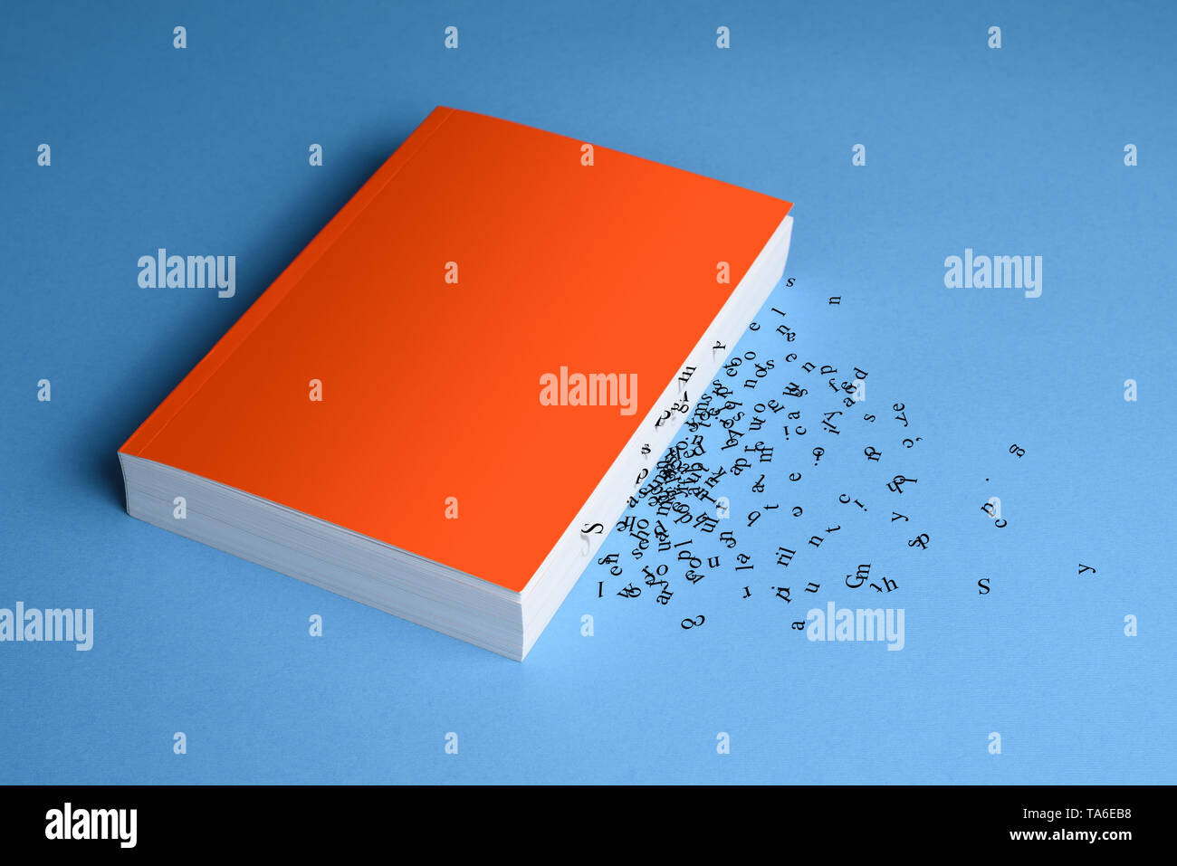 Mockup book with a soft orange cover. The concept of meaninglessness and confusion of information. Mixed letters and words. Inability to perceive info Stock Photo