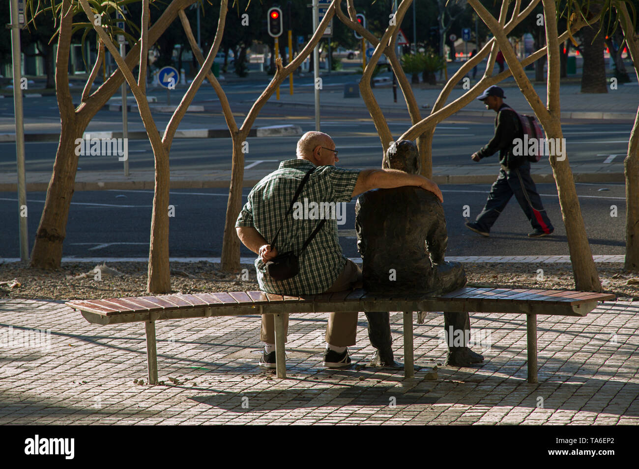 Man sitting with his arm around a statue in the centre of the city of Cape Town, South Africa. Stock Photo