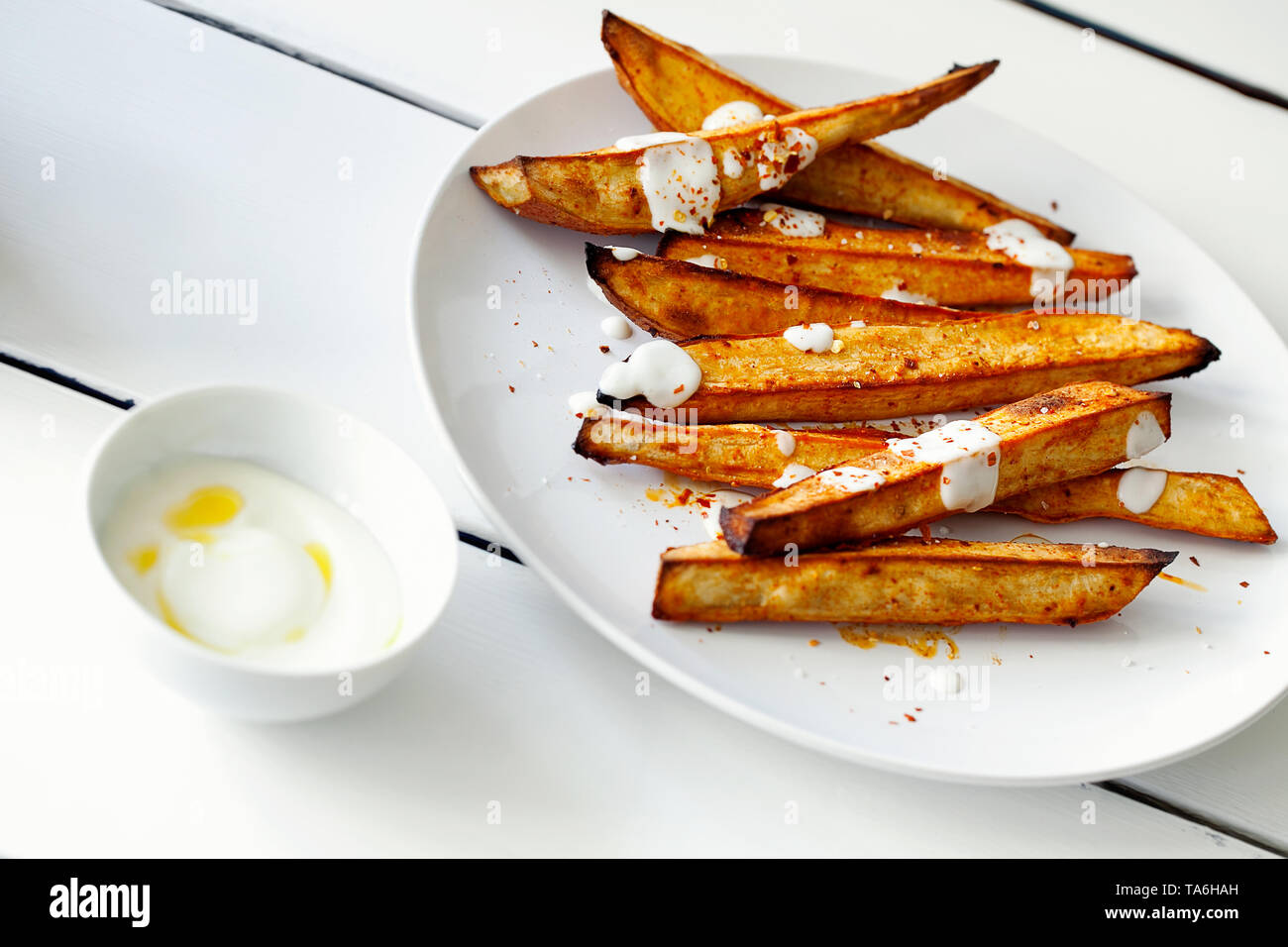 Homemade caramelized roasted sliced yams or sweet potato with Greek-style  yogurt and crushed red-pepper flakes close-up on white wooden background  Stock Photo - Alamy