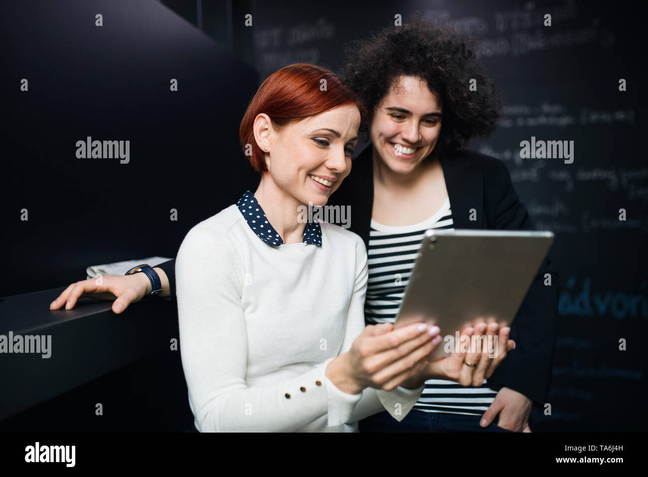 Two young businesspeople using tablet in office, start-up concept. Stock Photo
