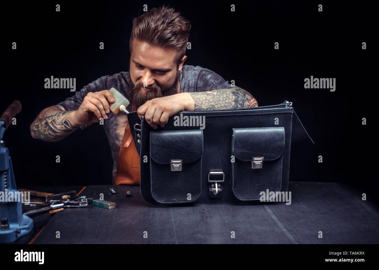 Craftsman working with leather processing a leather workpiece at a workshop Stock Photo
