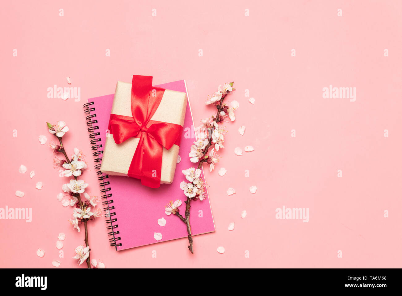 Top view notepad, gift box and flowers on a light pink background. Flat ...