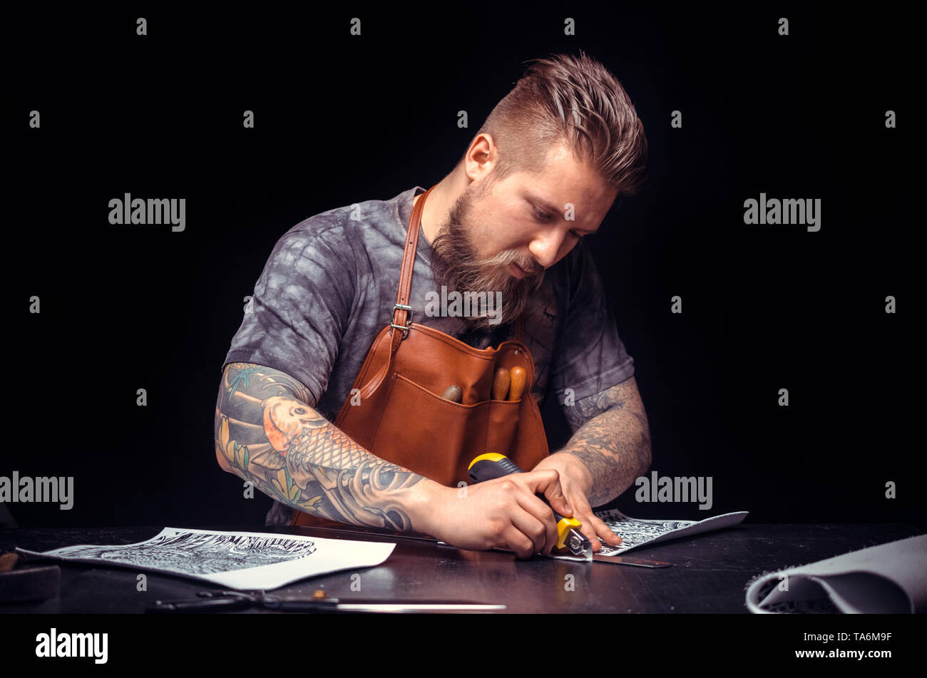 Leather Craftsman processing a leather workpiece in his tanner shop Stock Photo