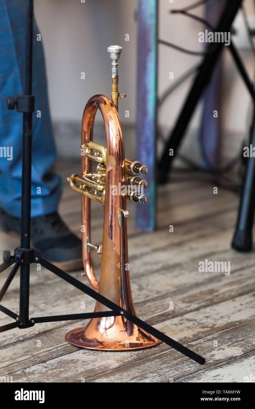 Vintage trumpet stands on grungy wooden floor. It is a brass instrument commonly used in classical and jazz ensembles Stock Photo