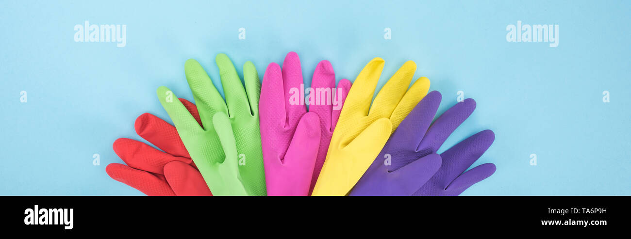 panoramic shot of multicolored rubber gloves on blue background Stock Photo