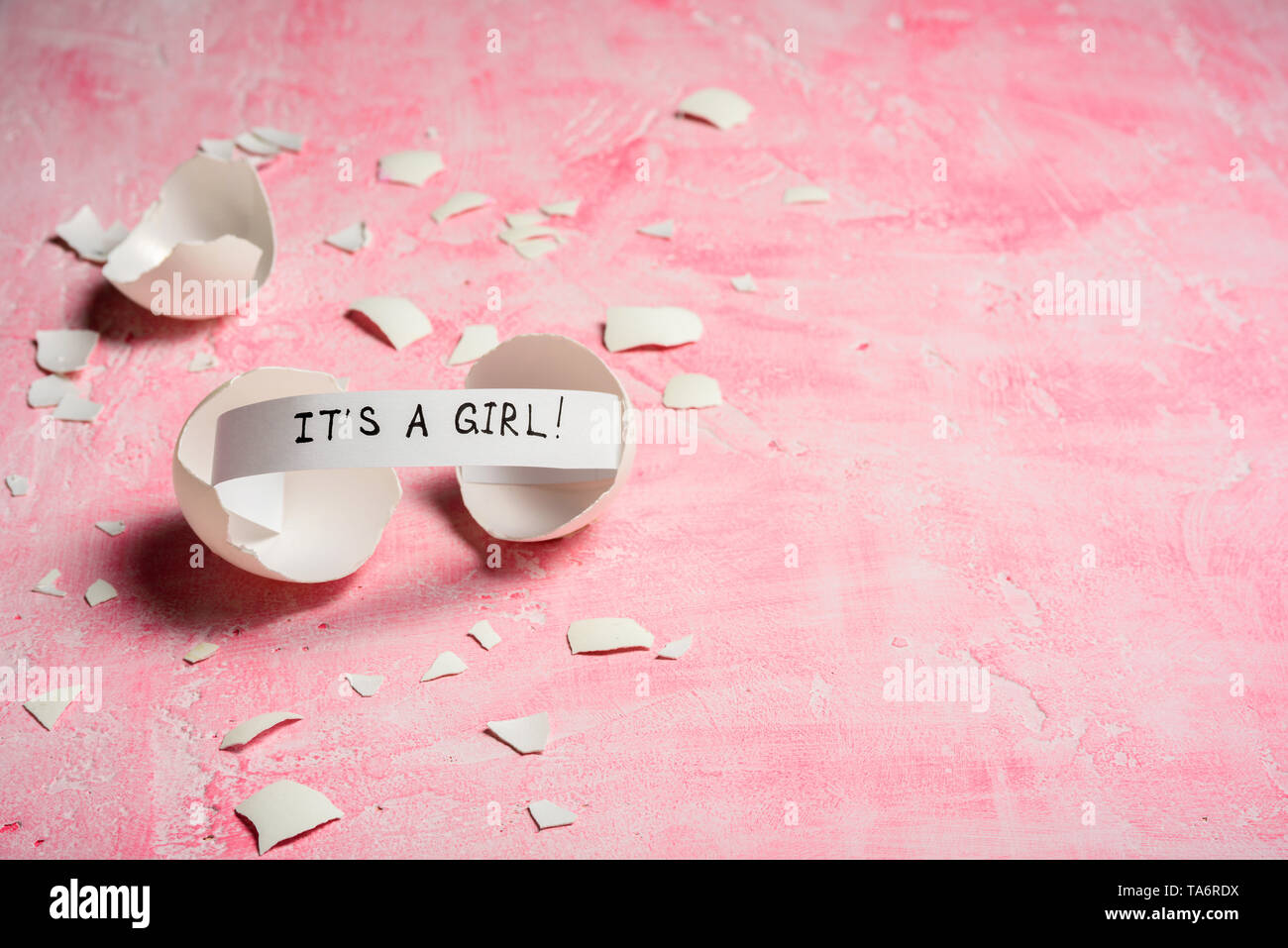 Baby shower concept. Girl, pink. Cracked egg with a message IT'S A GIRL. Like fortune cookies Stock Photo