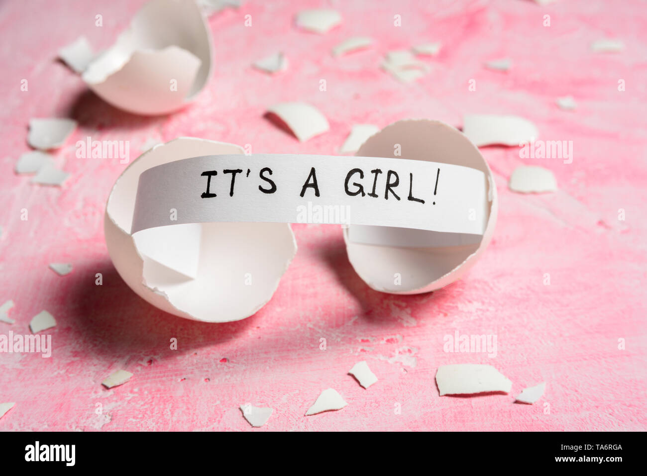 Baby shower concept. Girl, pink. Cracked egg with a message IT'S A GIRL. Like fortune cookies Stock Photo