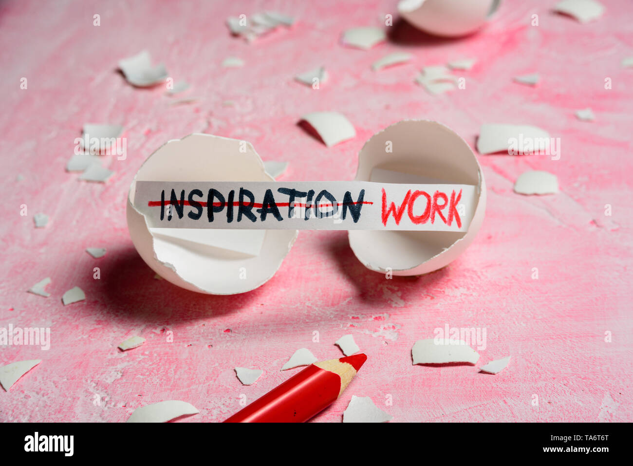 Work hard and inspiration concept. Cracked egg on pink background with text INSPIRATION and WORK. Like fortune cookies Stock Photo