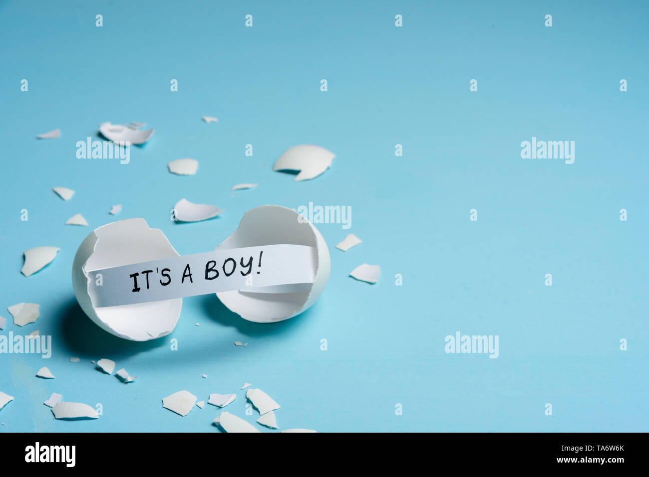 Baby shower concept. Boy, blue. Cracked egg with a message IT'S A BOY. Like fortune cookies Stock Photo