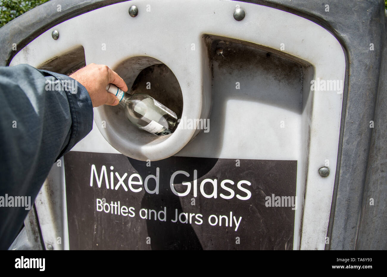 Putting glass bottles and jars into collection bin at local recycling