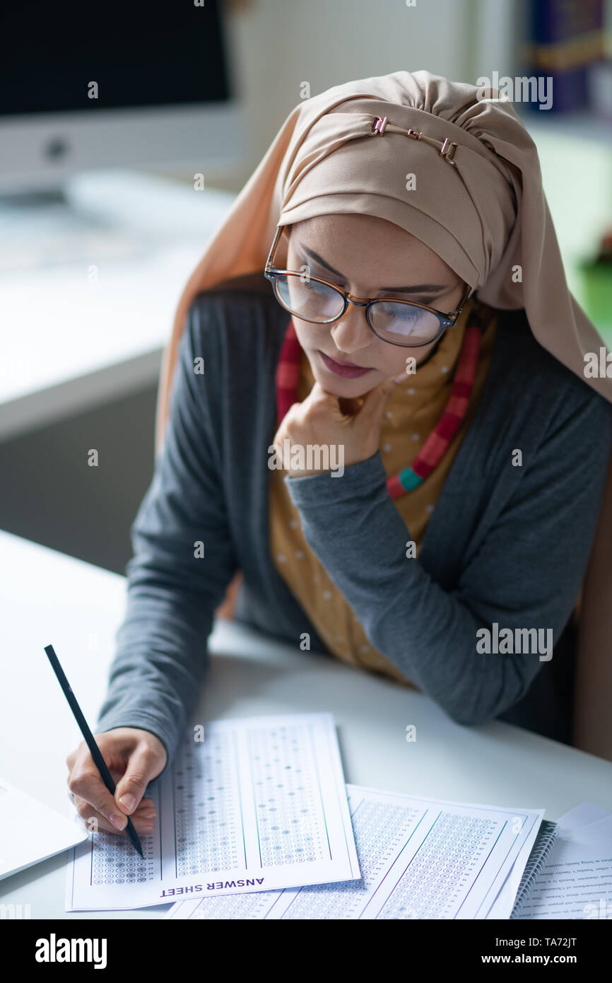 Teacher wearing glasses correcting tests of pupils Stock Photo Alamy