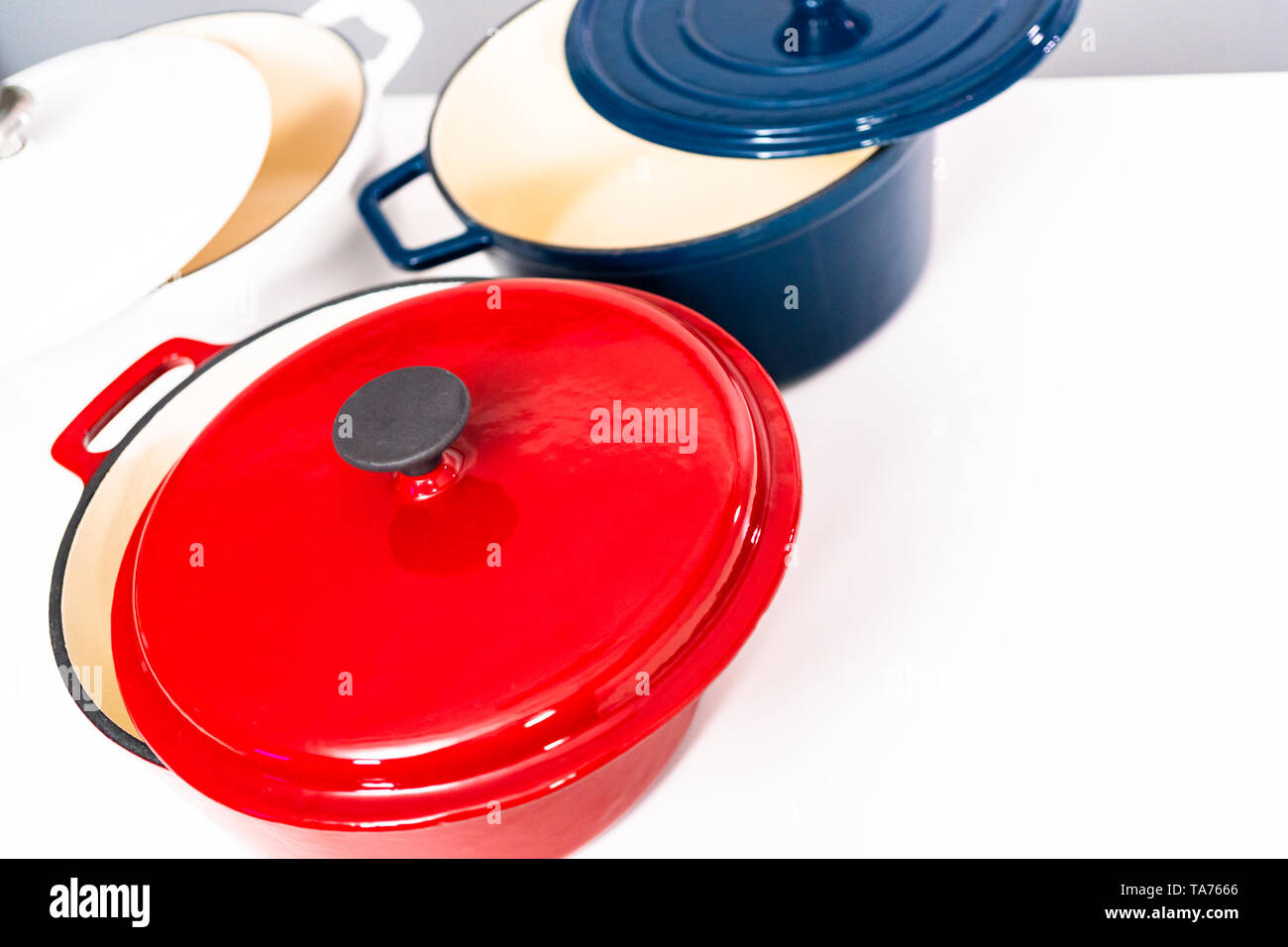 Red, white and blue enameled cast iron covered round dutch ovens on a whjite background. Stock Photo