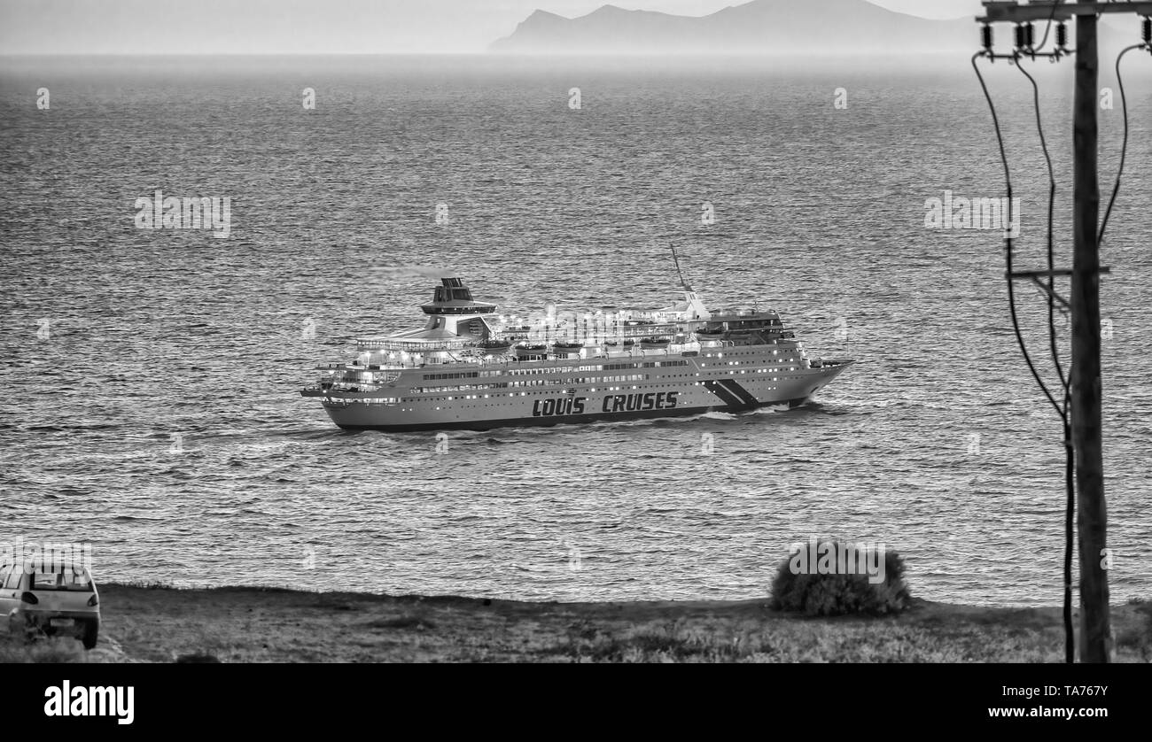 SANTORINI, GREECE - JUNE 2014: Sunset view of  departing cruise ship. Santorini is a major attraction for mediterranean cruises. Stock Photo