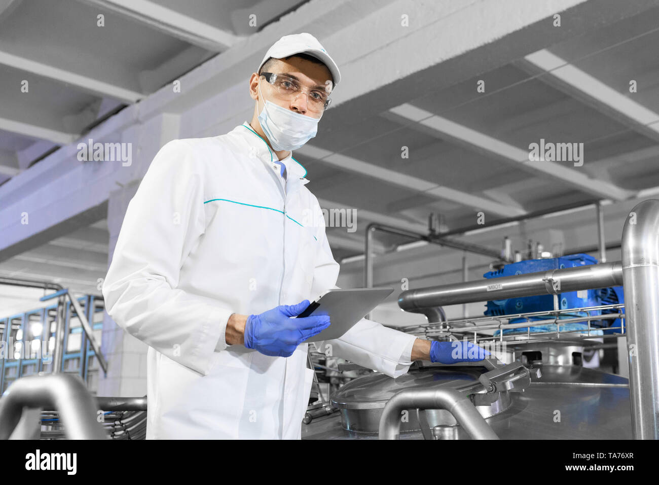 man in a white robe and a cap make an inspection of the production line Stock Photo