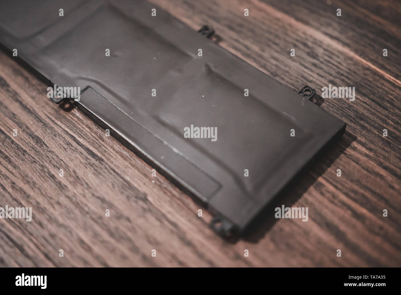 Swollen Lithium Polymer (Li-Po) laptop battery on a wooden table. Known ...