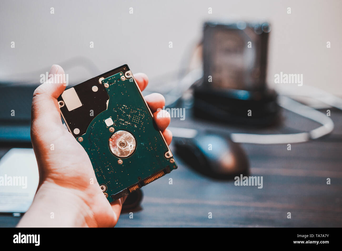 Hand holding laptop hard drive use to store files and data with desktop