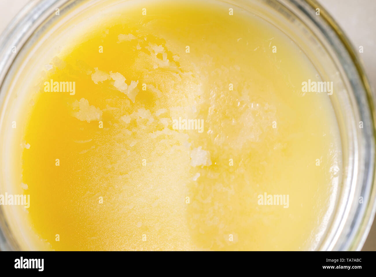 Homemade melted ghee clarified butter in open glass jar. Close up macro