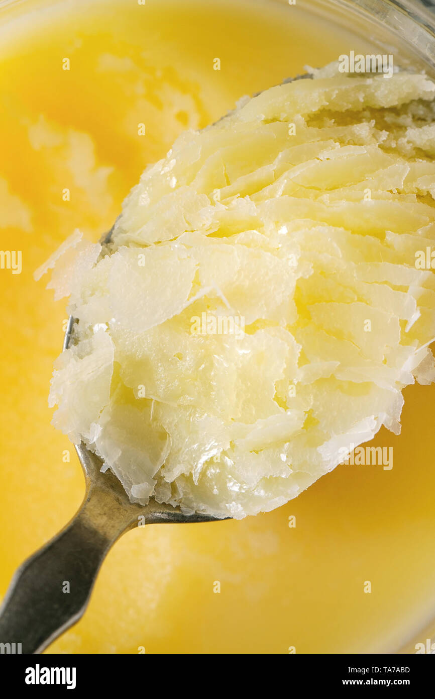 Homemade melted ghee clarified butter in open glass jar and spoon