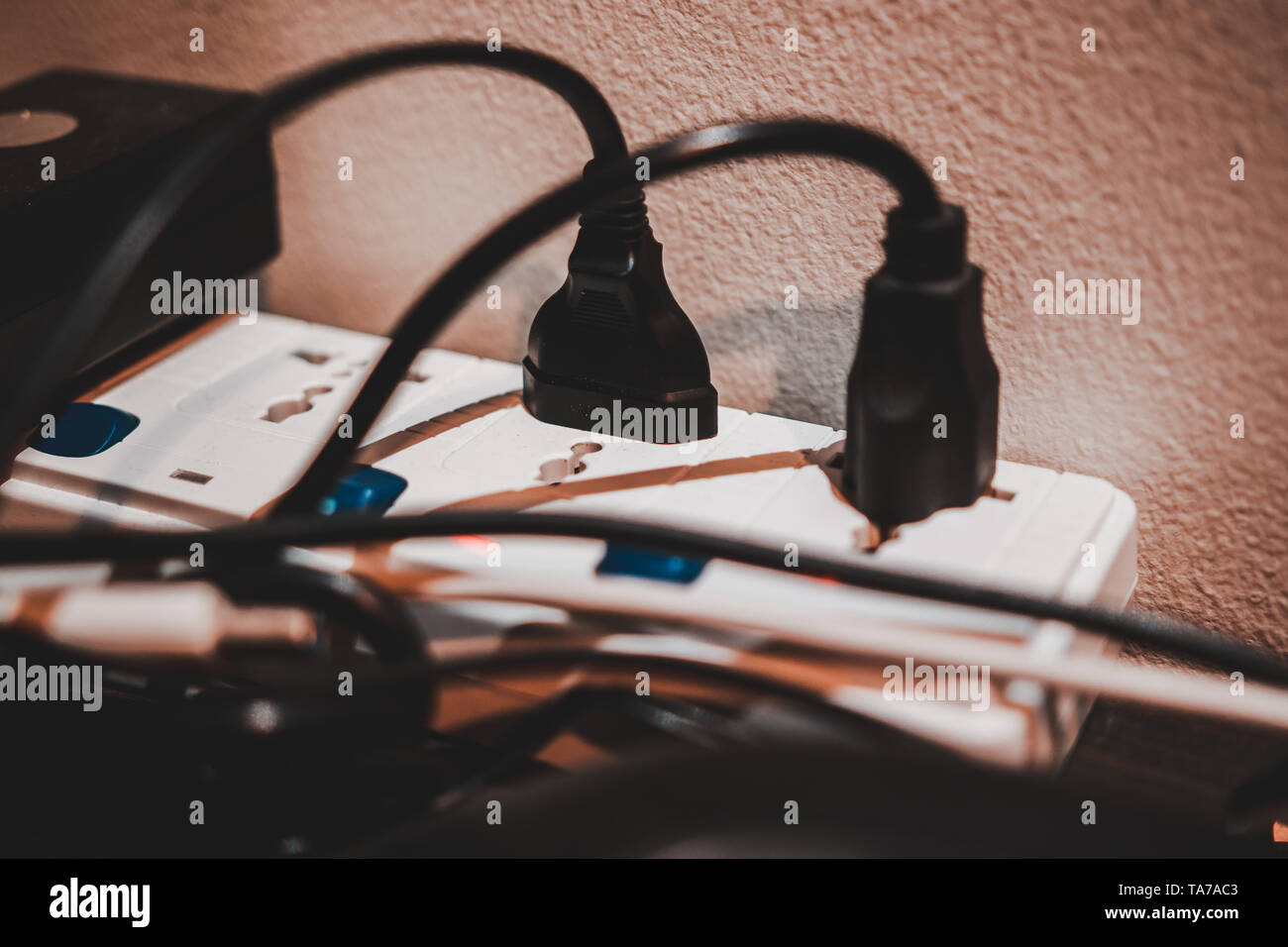 White extension cord on the desk with a lot of electric plugs plugged