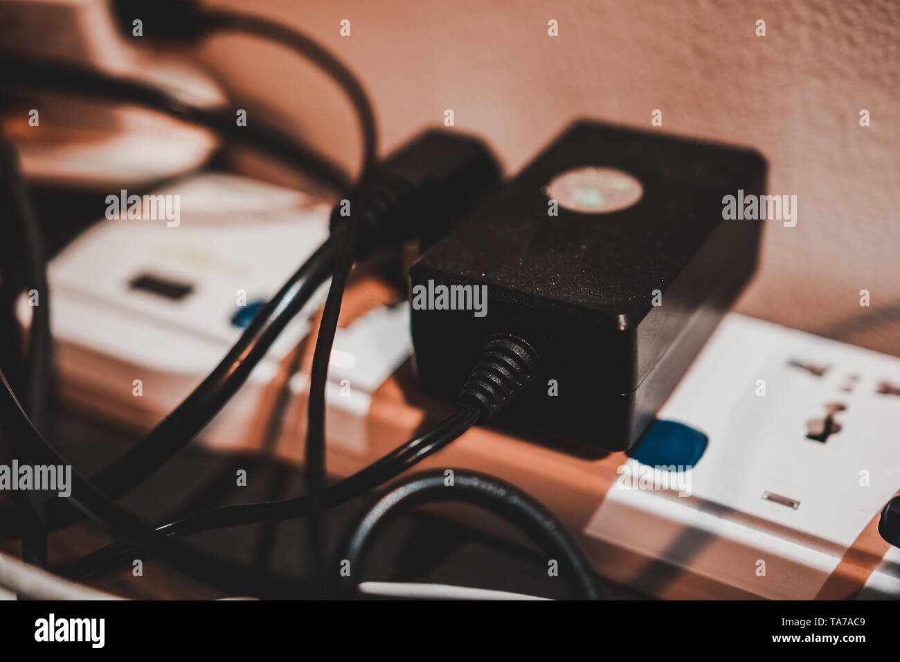 White extension cord on the desk with a lot of electric plugs plugged