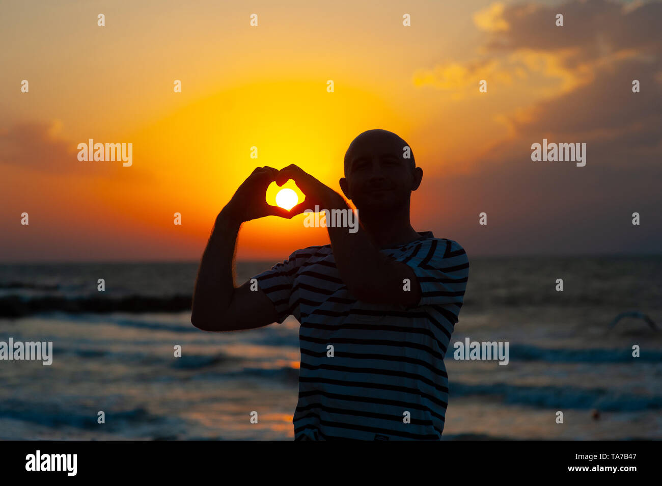 male hands in the form of heart against the sky pass sun beams. Hands ...