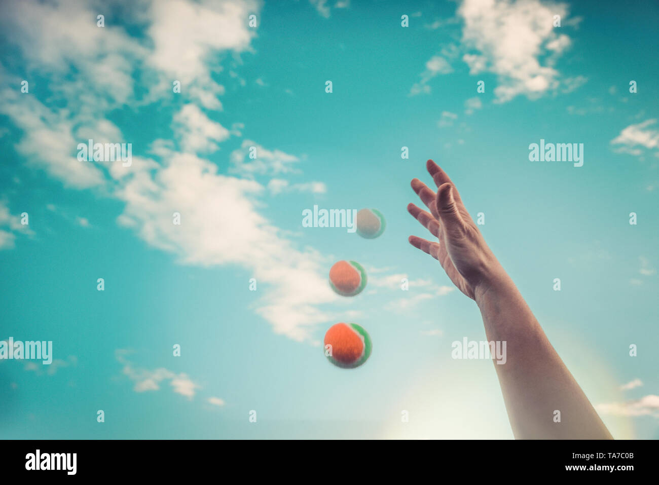 Tennis ball falls down from the hand. Against the sky. Summer fun