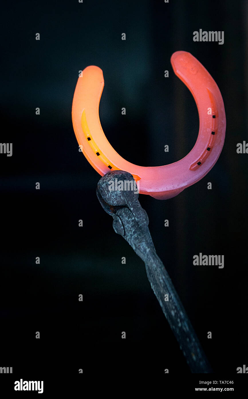 Red-hot horseshoe hold by pliers. Austria Stock Photo