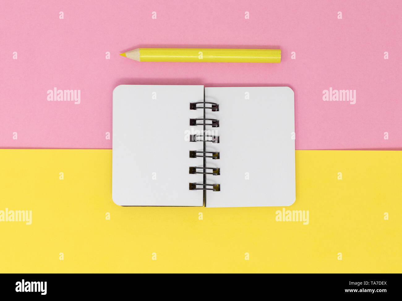 Open notebook and pencil on a yellow and pink background Stock Photo