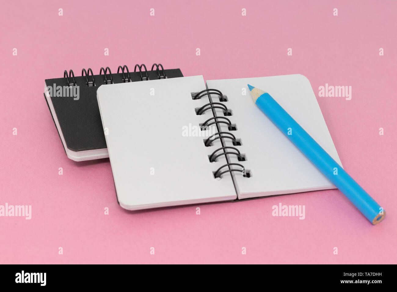 Two notebooks on a pink background with a blue pencil Stock Photo