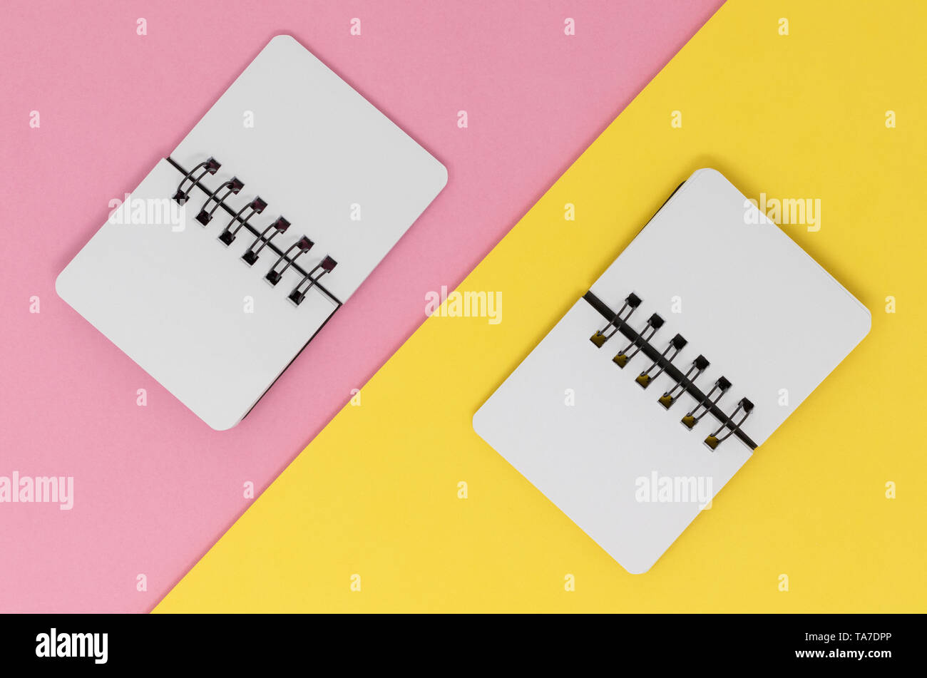 Two open notebooks on a pink and yellow diagonal background.Flat lay with copy space. Stock Photo