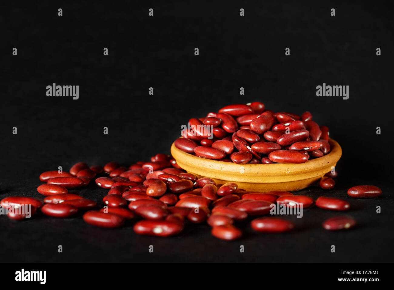 Common red beans -kidney bean - on black background , part of the beans are in a bowl Stock Photo