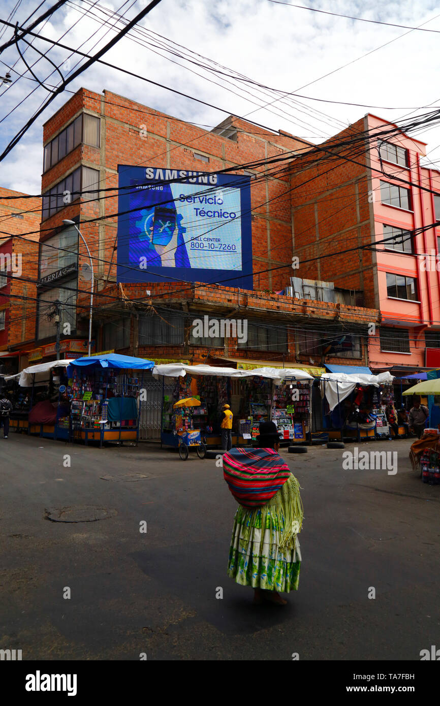 Aymara woman walking past a Samsung technical service electronic billboard in contraband electronics market area, La Paz, Bolivia Stock Photo