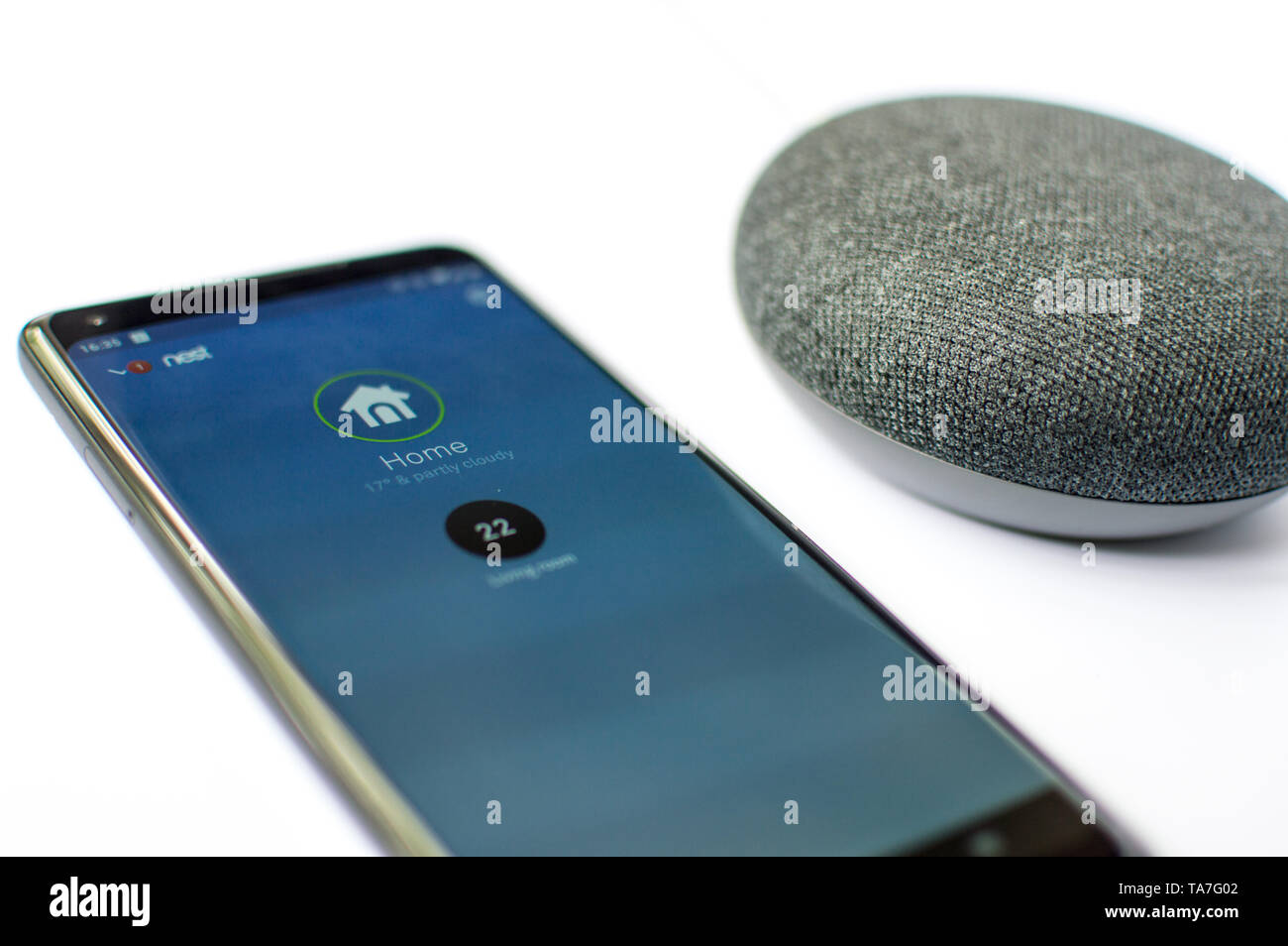 Google home mini with artificial intelligence and Nest thermostat service on an Android phone Stock Photo