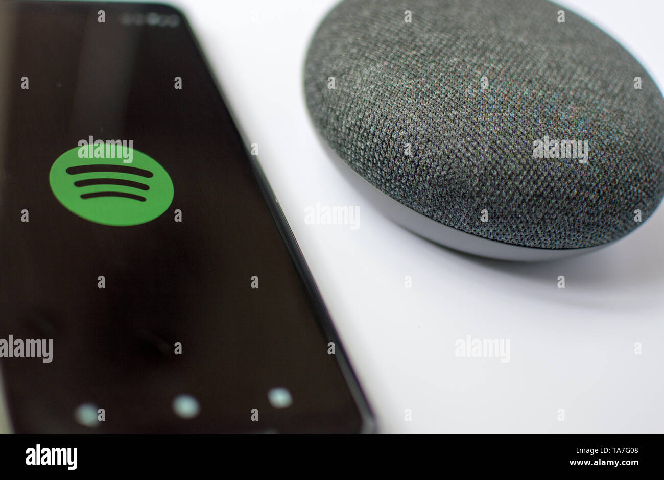 Google home mini with artificial intelligence and Spotify on an Android phone. Stock Photo