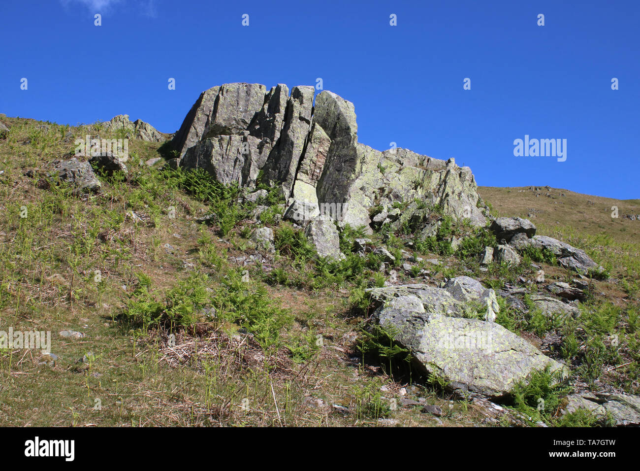Rocky outcrops on side Hallin Fell, an English Lake District fellside, Cumbria, United Kingdom seen against a blue sky on a sunny spring day. Stock Photo