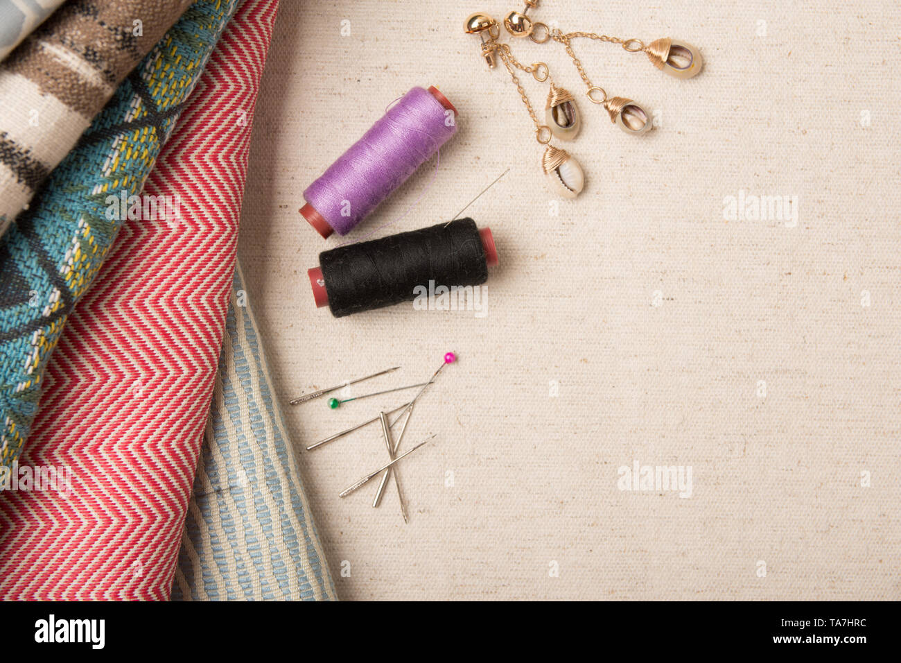 A variety of colourful fabric with assorted sewing pins and thread flat ...